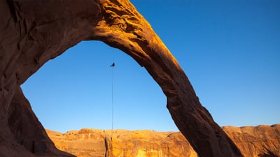 Bing wallpaper August 12, 2025. A man rappels off Corona Arch near Moab, Utah, United States (© Grant Ordelheide/TANDEM Stills + Motion)
